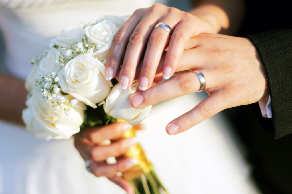 Wedding rings, bouqet and hands holding.