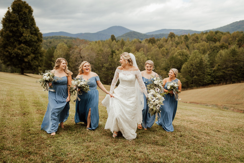 A bride and bridesmaids running through the R - Ranch.