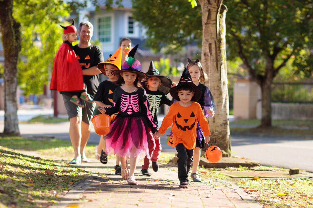 Child in Halloween costume. Little boy and girl with pumpkin lantern and candy bucket. Baby in witch hat. Autumn holiday fun.