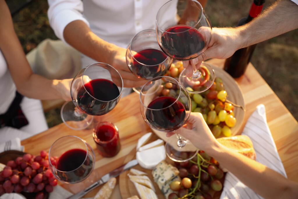 Friends holding glasses of wine at table, closeup